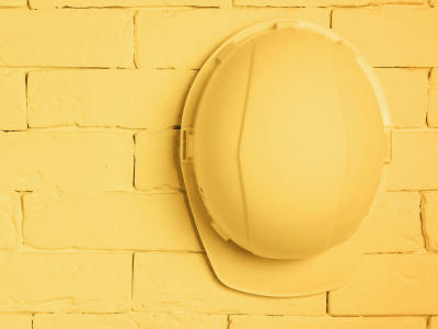 Yellow construction helmet on a yellow brick wall.